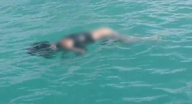 Vítima estava despida da cintura para baixo; corpo foi retirado do mar com a ajuda de pescadores (Crédito: Reprodução/Vídeo)