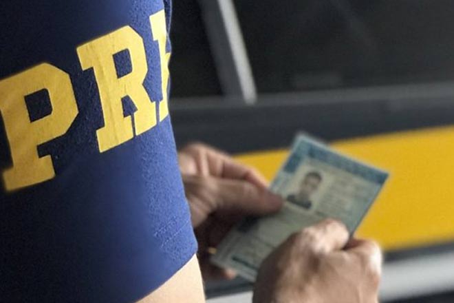 Agente da PRF segurando uma carteira de habilitação