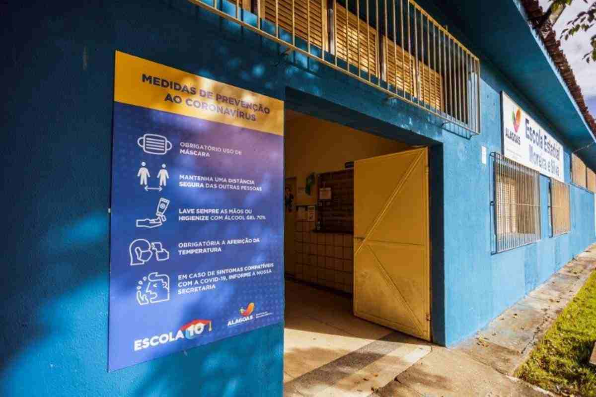 Placa com medidas de prevenção à Covid colocada na porta de escola no Cepa — © Agência Alagoas