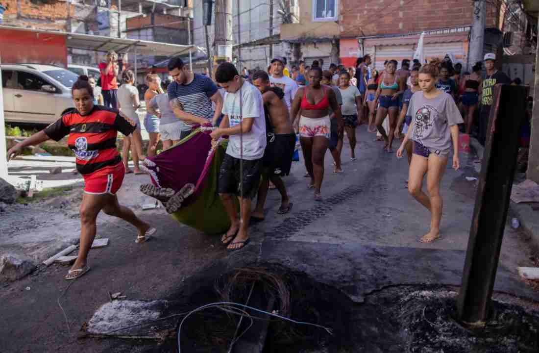 Vítima morta sendo carregada por moradores do Complexo do Alemão | © Eduardo Anizelli/Folhapress