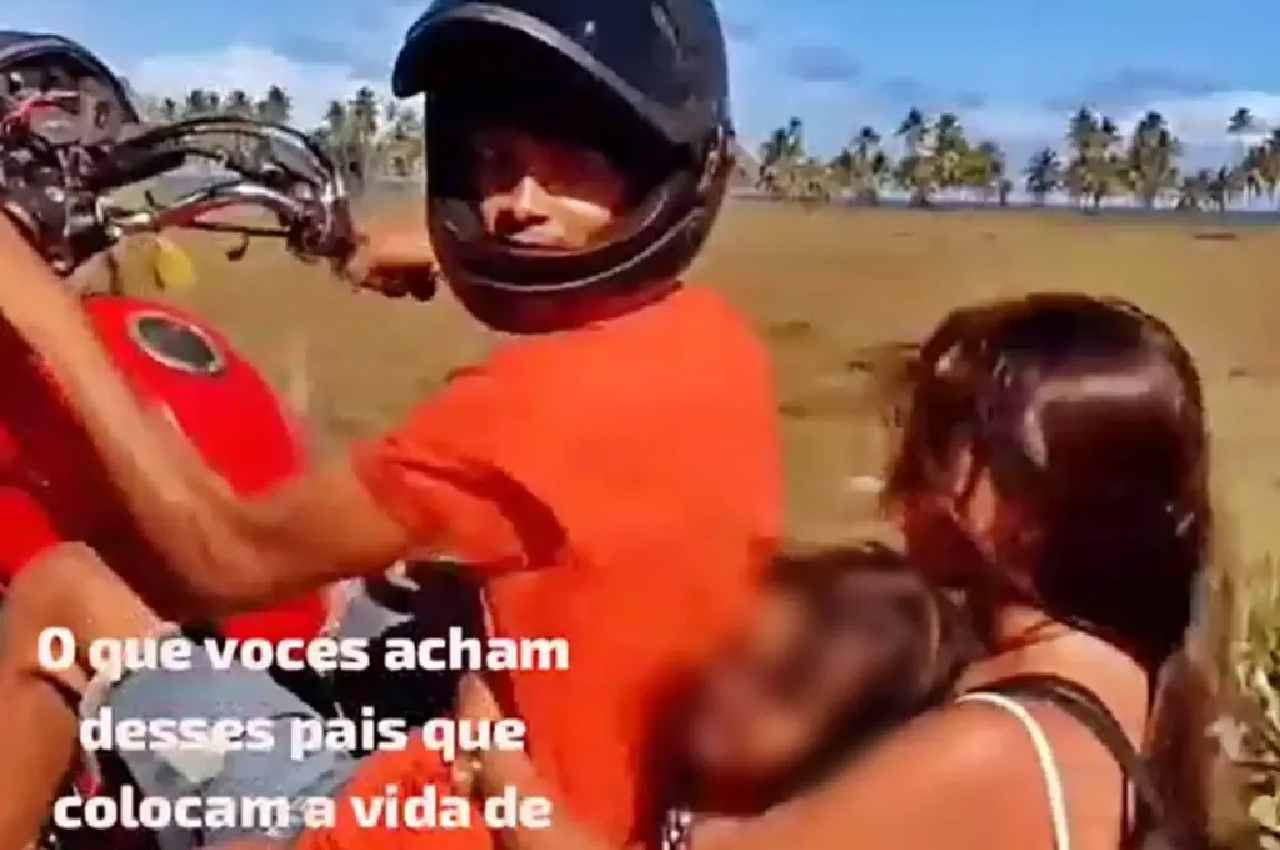 Motociclista empinando moto com passageira e criança a bordo e sem capacete | © Reprodução 