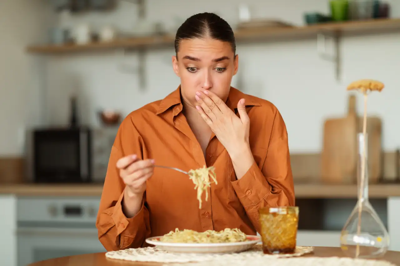 Mulher com nauseas comendo espaguete - @Reprodução