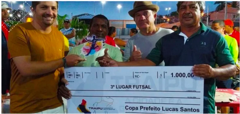 atletas e organizadores seguram cheque de premiacao do terceiro lugar do futsal na copa prefeito lucas santos em traipu
