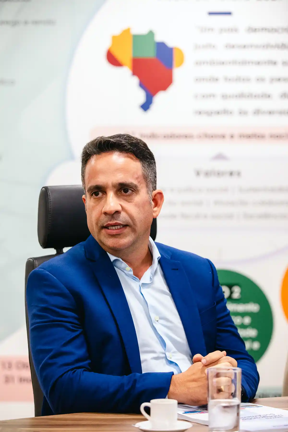 governador de Alagoas Paulo Dantas sentado em reunião com terno azul e fundo institucional desfocado governador de Alagoas Paulo Dantas sentado em reunião com terno azul e fundo institucional desfocado