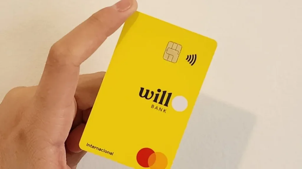 mão segura cartão amarelo do Will Bank com chip e símbolo de pagamento por aproximação em close