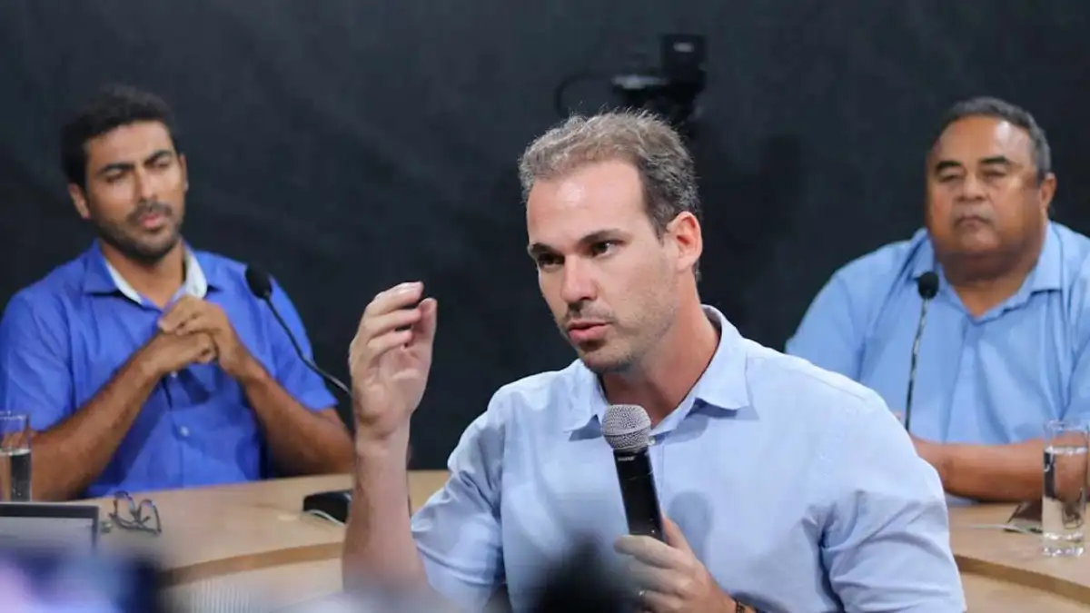 Olavo Neto em entrevista ao BR104, em ambiente interno, durante conversa com equipe e microfone ao lado Olavo Neto em entrevista ao BR104, em ambiente interno, durante conversa com equipe e microfone ao lado