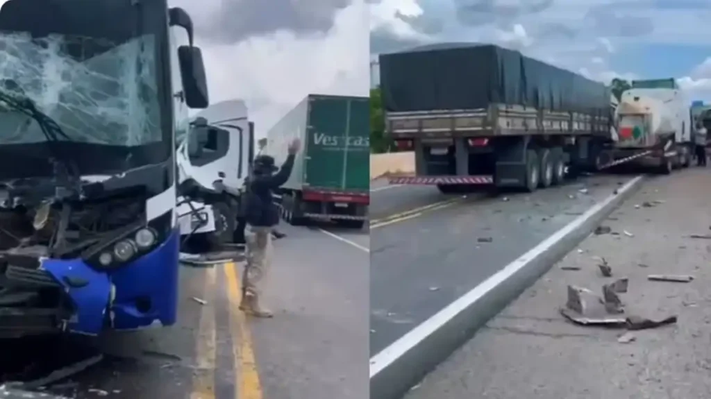 Ônibus com frente destruída após acidente em rodovia, com caminhões parados e destroços na pista durante atendimento da ocorrência