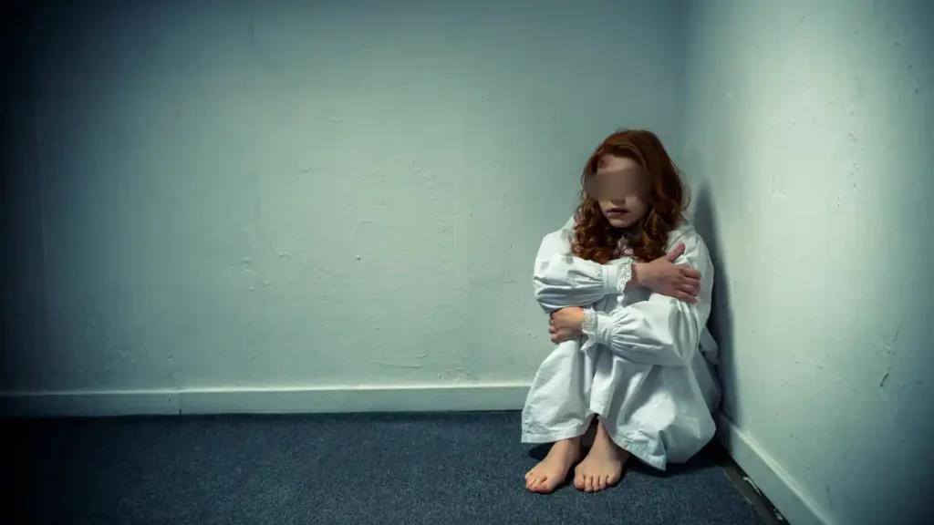 pessoa-sentada-no-chao-em-canto-de-quarto-com-expressao-de-medo-em-ambiente-clinico