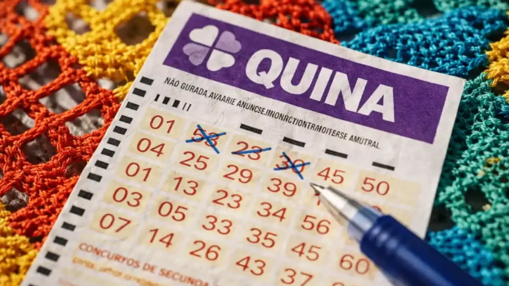 Cartela da Quina com números marcados e caneta sobre renda filé colorida, em imagem ilustrativa de aposta e resultado