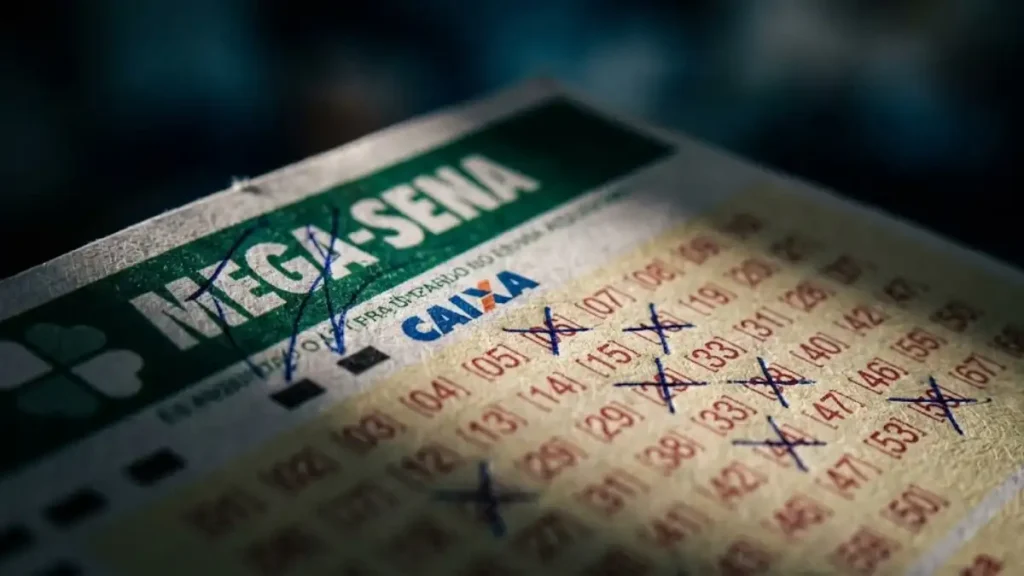 volante da Mega-Sena da Caixa com dezenas marcadas a caneta em close e fundo desfocado