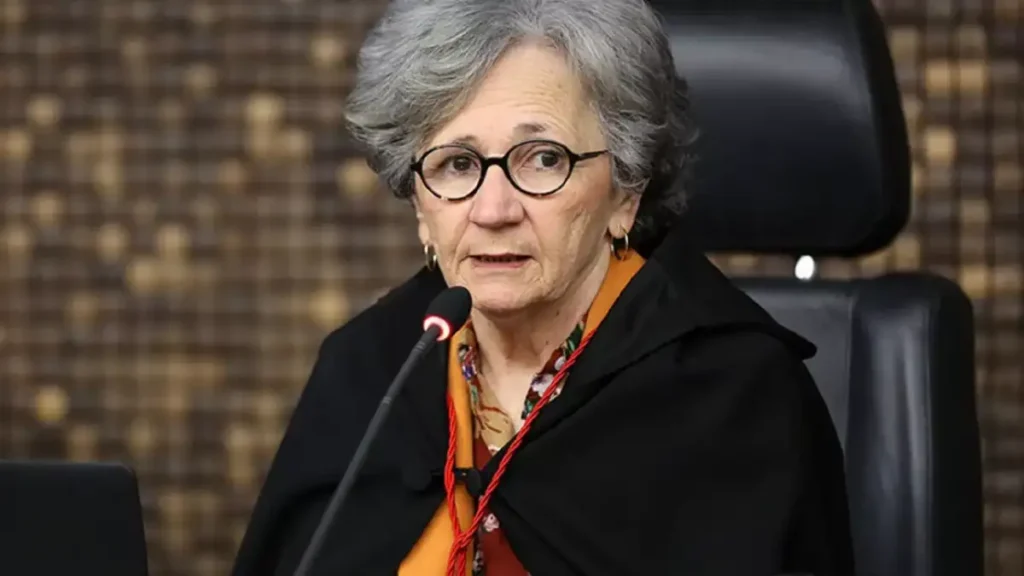 Desembargadora Elisabeth Carvalho Nascimento fala ao microfone durante sessão, sentada em cadeira de plenário, usando óculos e capa preta