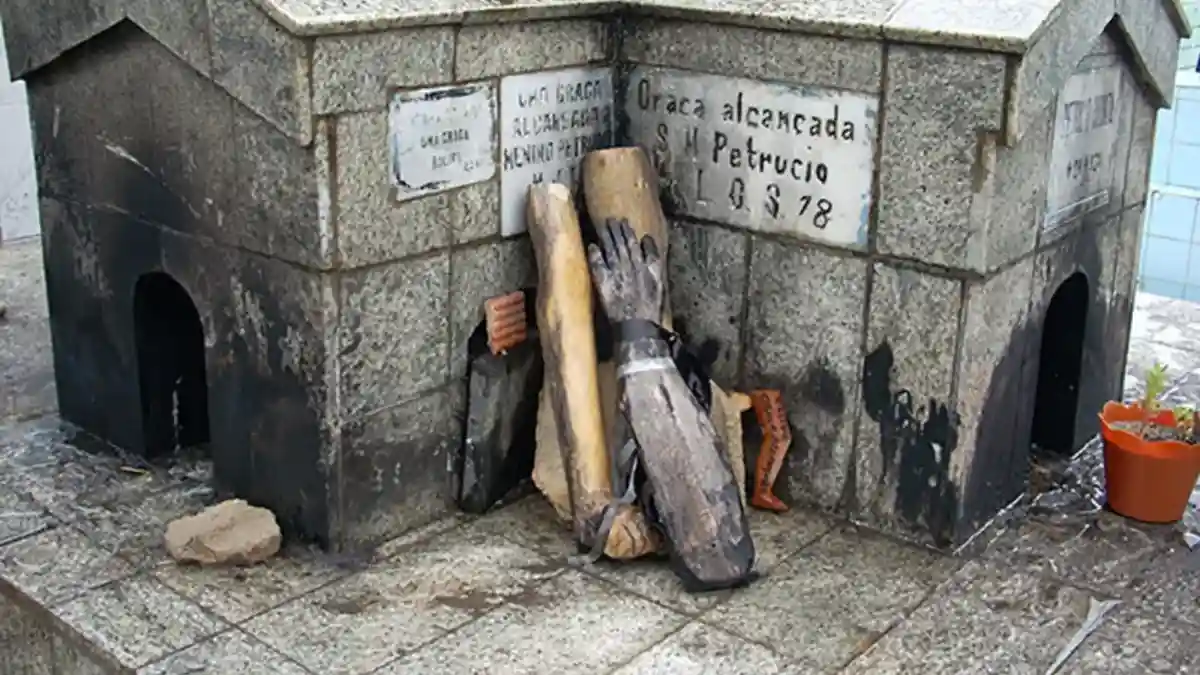 Túmulo do Menino Petrúcio em cemitério de Maceió com placas de agradecimento e objetos deixados por devotos